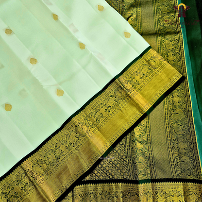 A graceful pearl white body adorned with delicate gold zari buttas, lending a refined and sophisticated Saree