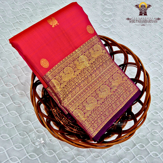A bright vermilion red with a rich violet/purple border Saree