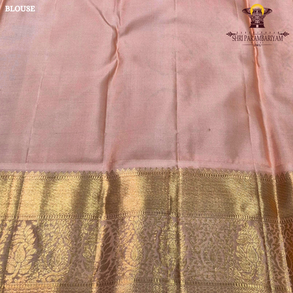 A deep bottle green with antique gold zari weaving, paired with a soft peach-pink korvai border Saree