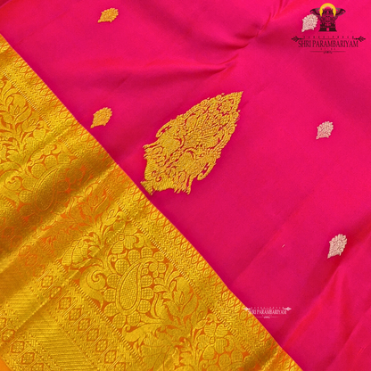 Bright rani pink (vibrant magenta tone) with a rich gold zari border and orange edging Saree