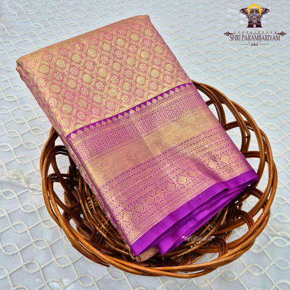 A Soft pastel peach with rich gold zari work and a contrasting deep magenta (rani pink) border Saree