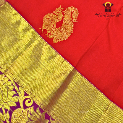 A vibrant red with rich gold zari border and contrast purple edging Saree