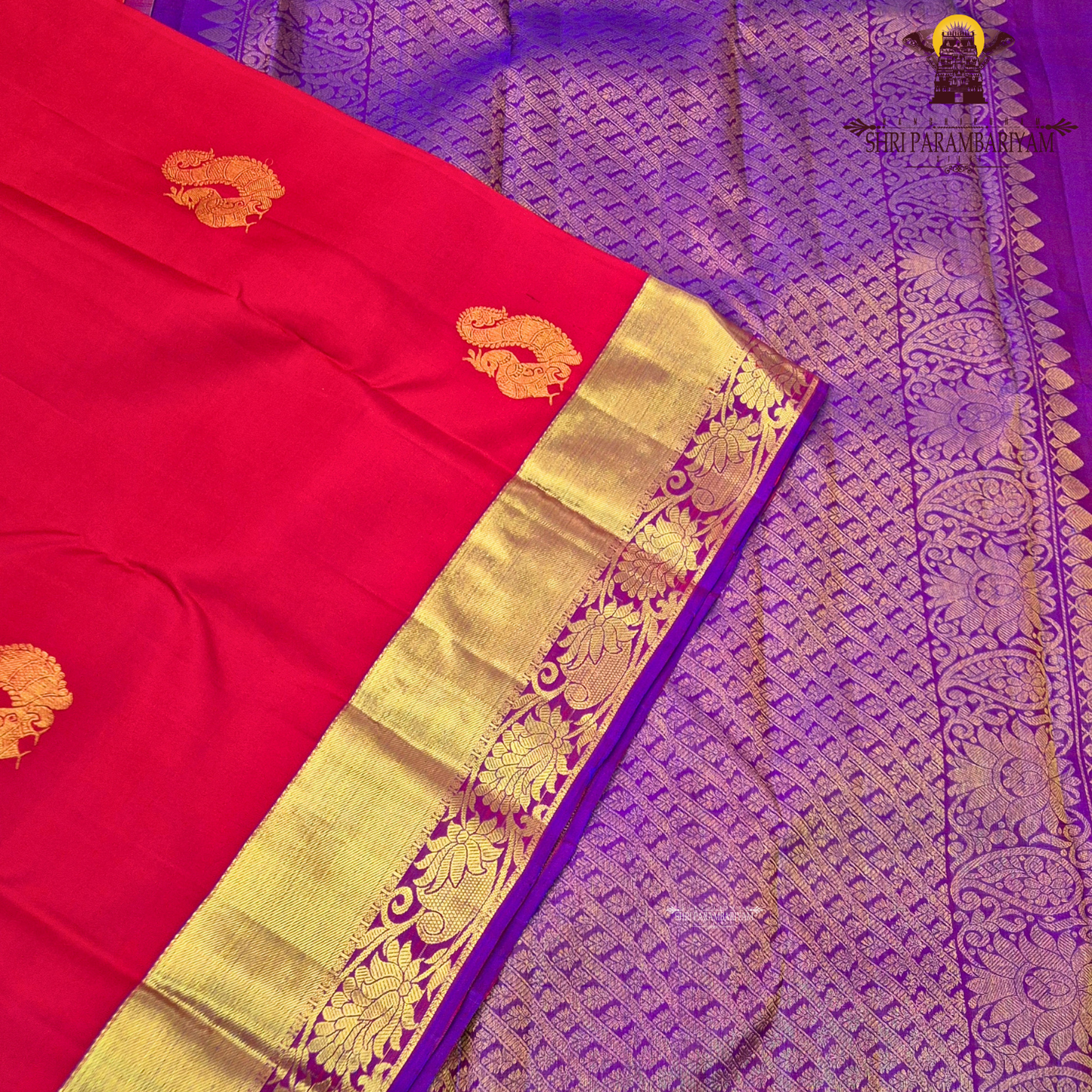 A vibrant red with rich gold zari border and contrast purple edging Saree